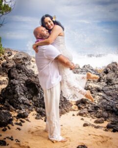 A man and woman are hugging on the beach.