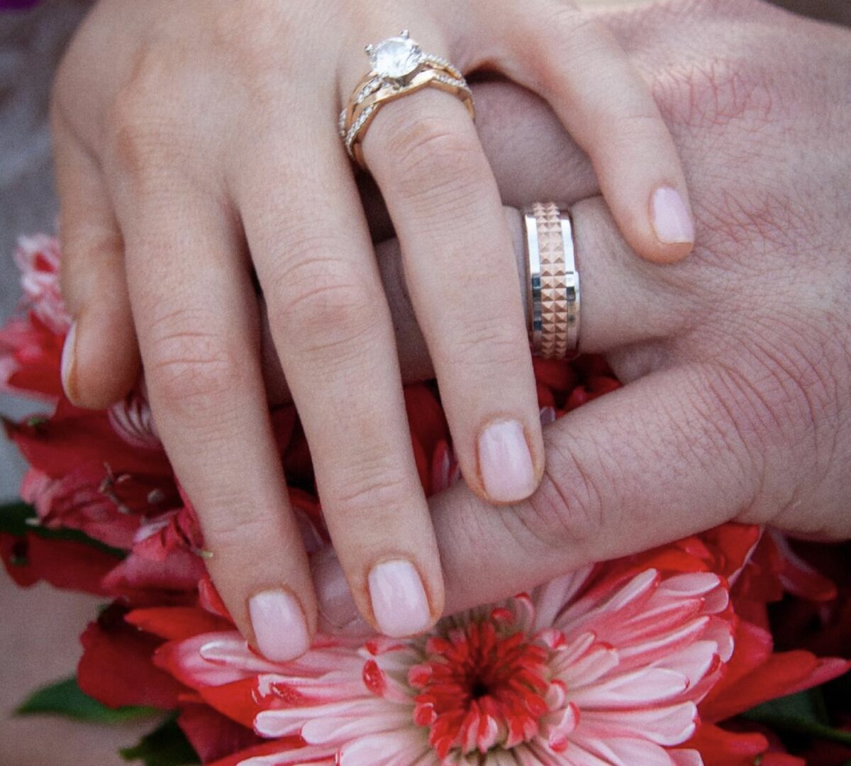 A close up of two hands with wedding rings on