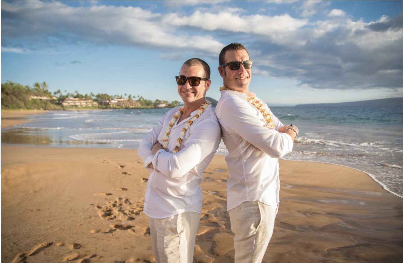 Two men standing on the beach in white clothes