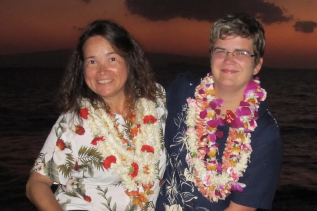 Two women standing next to each other wearing leis.
